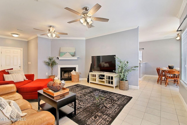 living room featuring a ceiling fan, baseboards, a fireplace, ornamental molding, and tile patterned flooring