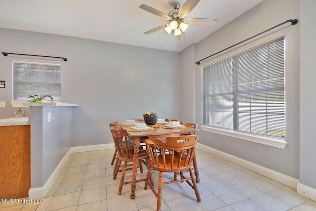 dining space with baseboards, light tile patterned flooring, and a ceiling fan