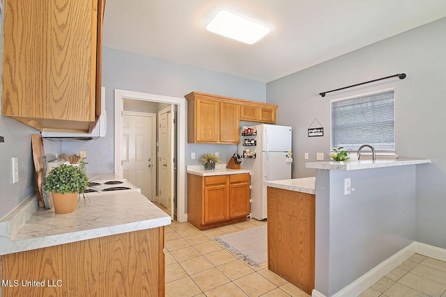 kitchen with baseboards, light countertops, light tile patterned floors, freestanding refrigerator, and a sink