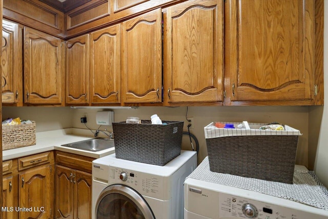 clothes washing area with washer and dryer, cabinets, and sink