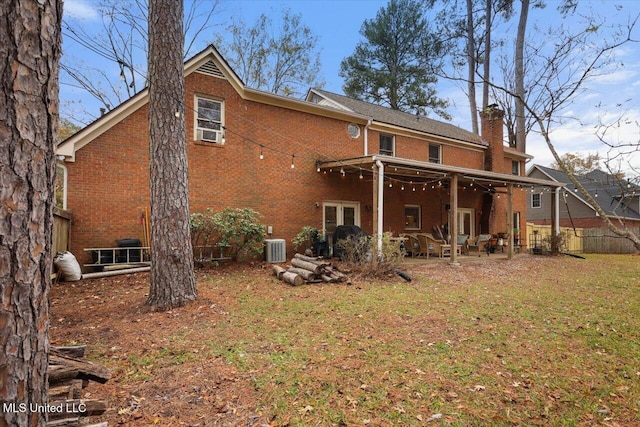 rear view of property with cooling unit, a patio area, and a lawn