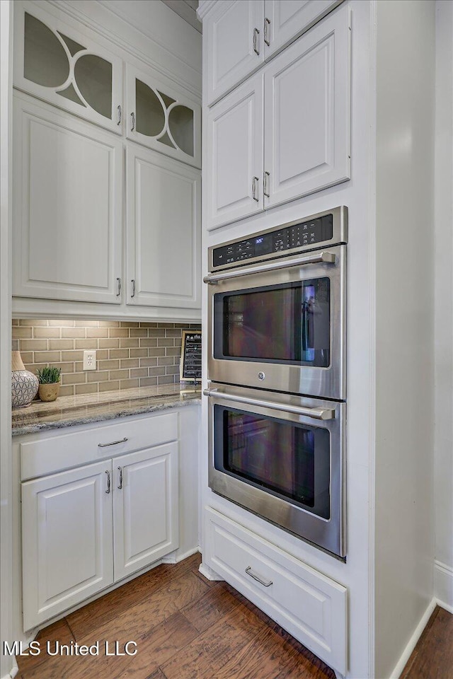 kitchen with white cabinetry, dark hardwood / wood-style flooring, double oven, and light stone counters