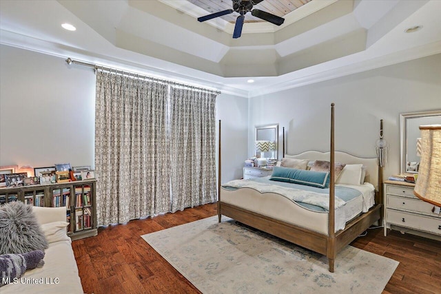 bedroom with a raised ceiling, crown molding, dark wood-type flooring, and ceiling fan