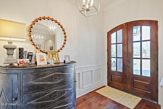 foyer entrance featuring ornamental molding, dark hardwood / wood-style floors, a notable chandelier, and french doors