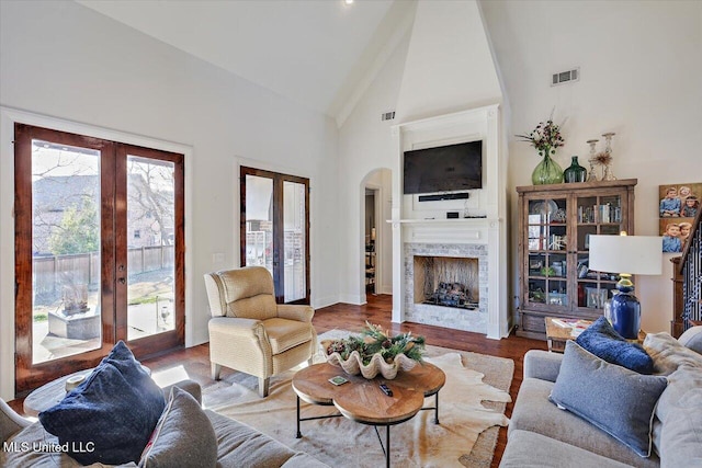 living room with french doors, wood-type flooring, a fireplace, and high vaulted ceiling