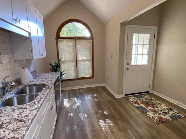 kitchen with white cabinets, light stone countertops, sink, and vaulted ceiling