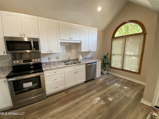 kitchen featuring appliances with stainless steel finishes, sink, white cabinetry, vaulted ceiling, and decorative backsplash