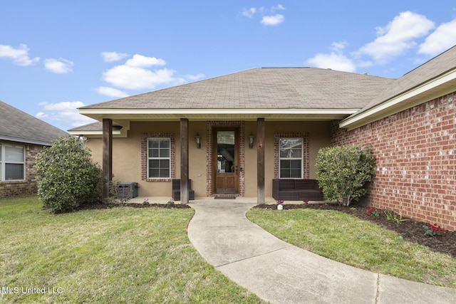 view of front facade featuring covered porch, a shingled roof, a front yard, and stucco siding