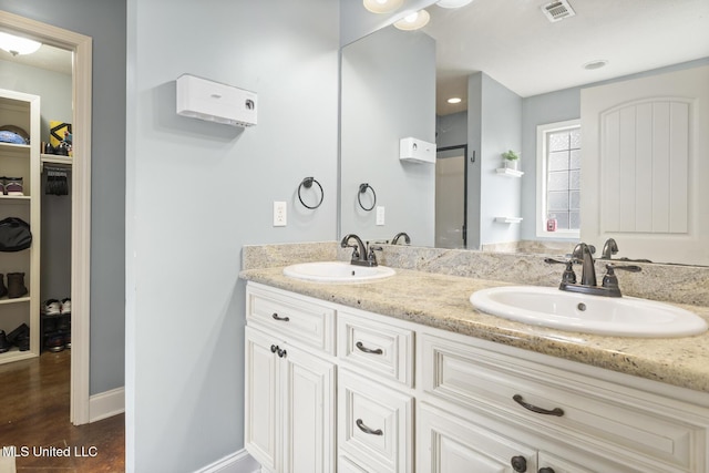 bathroom featuring a sink, visible vents, wood finished floors, and a spacious closet