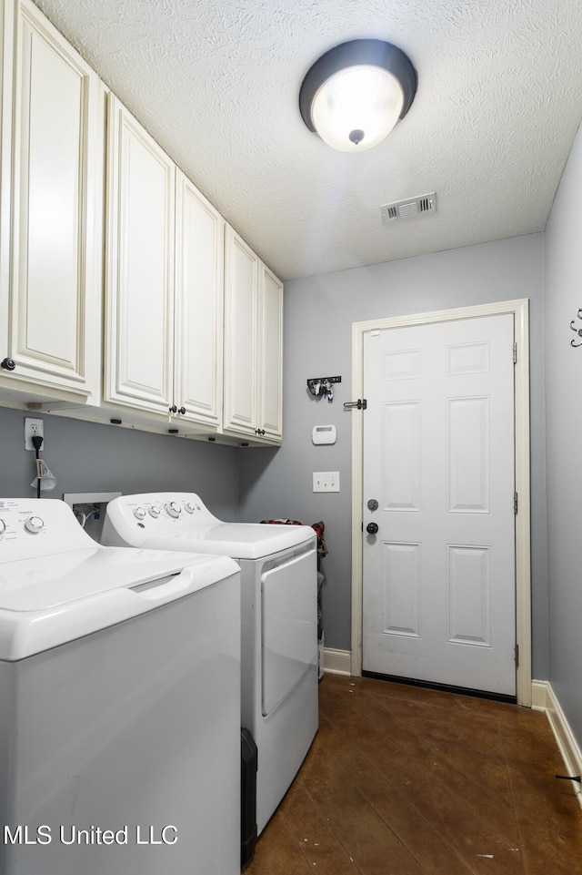 laundry area featuring visible vents, a textured ceiling, cabinet space, separate washer and dryer, and baseboards