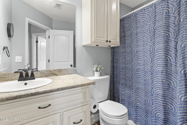 bathroom with vanity, toilet, and visible vents