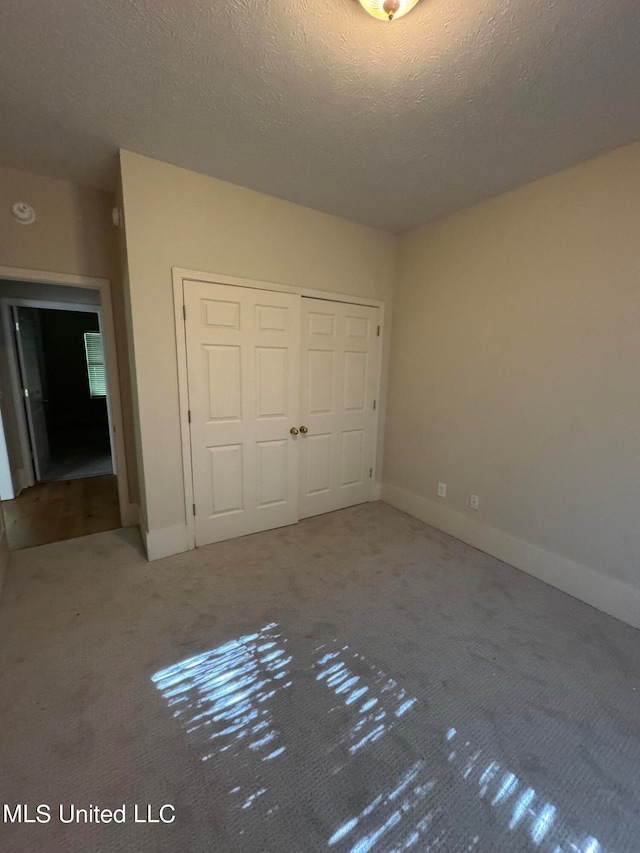 unfurnished bedroom featuring a closet, a textured ceiling, and carpet flooring