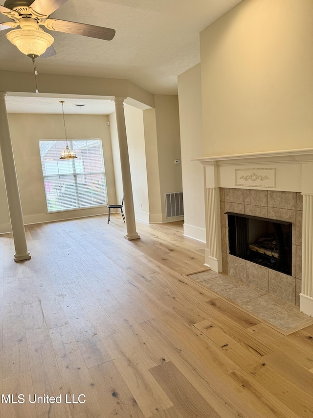 110 Cowles Creek Rd, Clinton, MS 39056 - unfurnished living room with decorative columns, ceiling fan, a tiled fireplace, and wood-type flooring