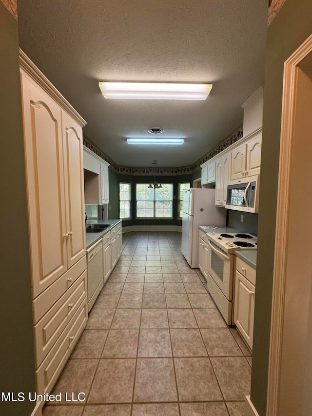 kitchen with sink, a textured ceiling, white appliances, and light tile patterned floors