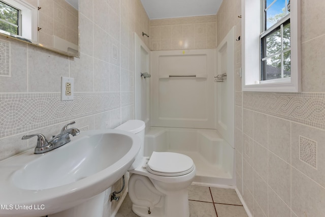 full bathroom featuring toilet, tile walls, tile patterned floors, a sink, and a stall shower