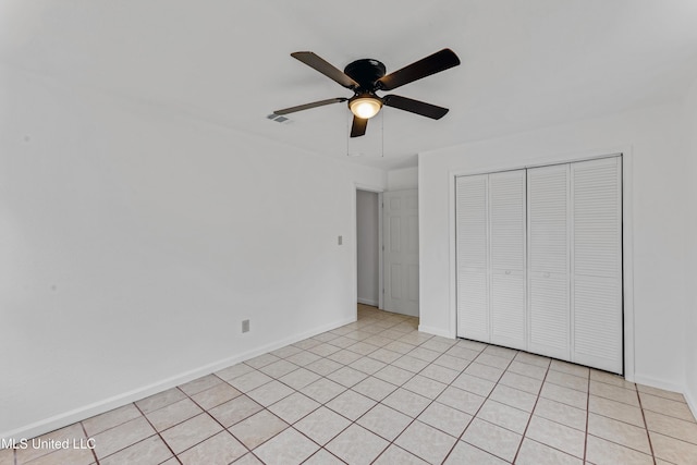 unfurnished bedroom featuring ceiling fan, baseboards, light tile patterned floors, visible vents, and a closet