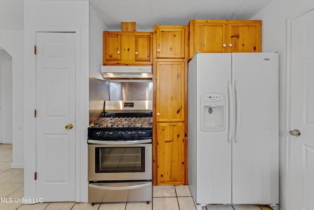 kitchen featuring under cabinet range hood, light tile patterned flooring, white refrigerator with ice dispenser, and stainless steel gas stove