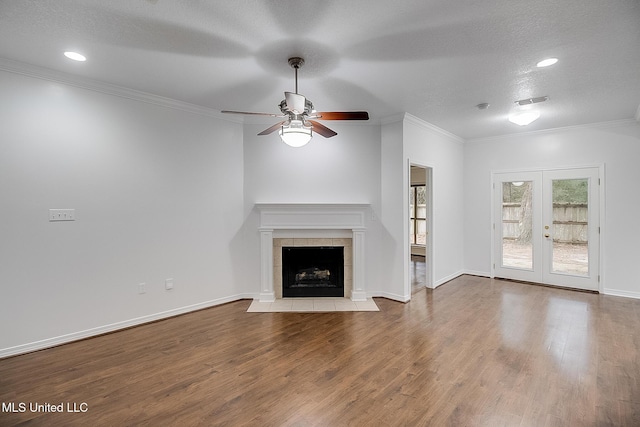 unfurnished living room with french doors, crown molding, a textured ceiling, a fireplace, and light hardwood / wood-style floors