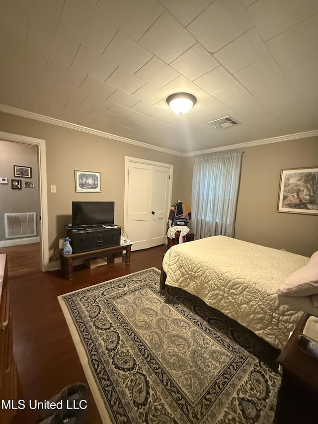 bedroom with visible vents, ornamental molding, baseboards, and wood finished floors