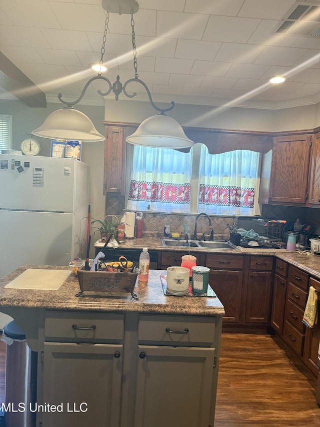 kitchen with dark wood finished floors, decorative backsplash, a sink, and a center island