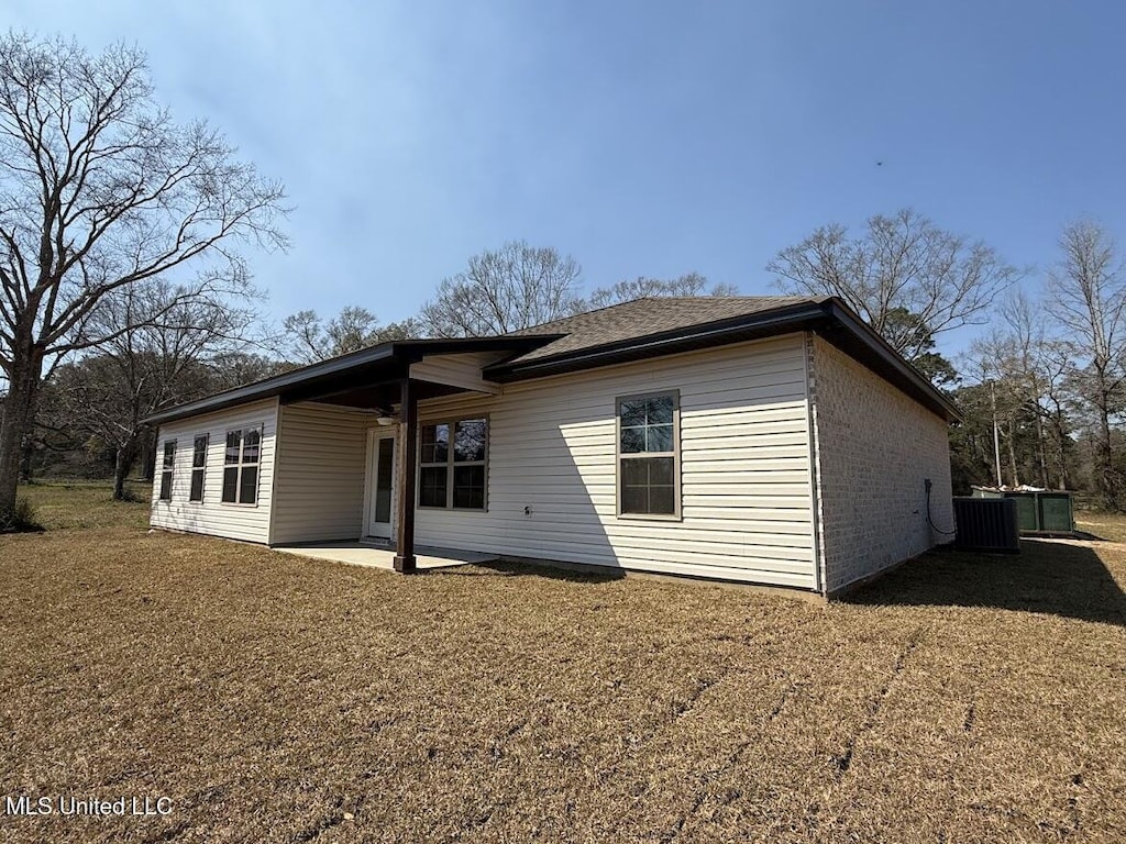 back of house featuring brick siding, a lawn, cooling unit, and a patio