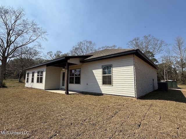 back of house featuring brick siding, a lawn, cooling unit, and a patio