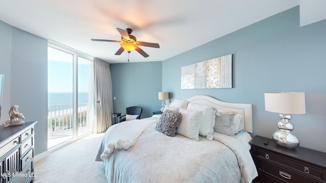 carpeted bedroom featuring access to outside, a water view, a wall of windows, and ceiling fan