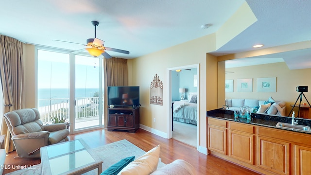 living room with ceiling fan, sink, and light hardwood / wood-style floors