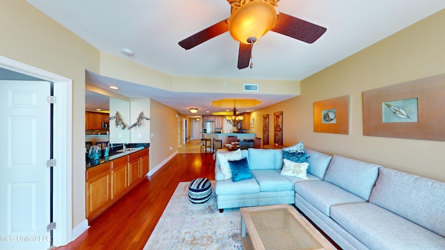 living room with ceiling fan with notable chandelier and dark hardwood / wood-style flooring