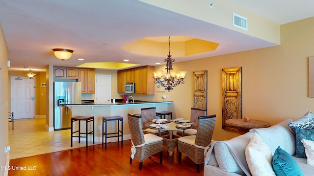 dining area with a chandelier, sink, and light hardwood / wood-style flooring