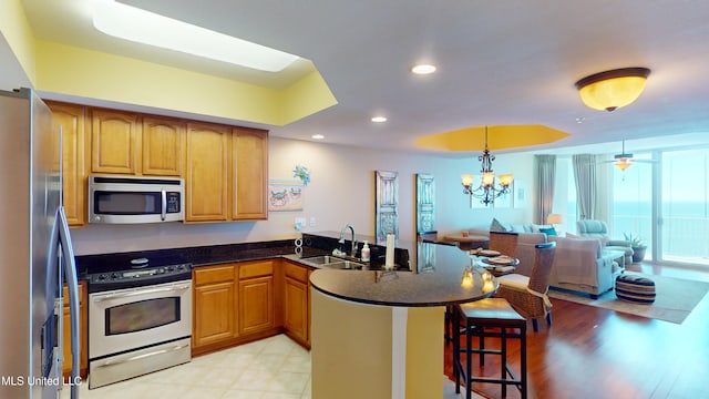 kitchen featuring kitchen peninsula, a breakfast bar area, sink, light wood-type flooring, and appliances with stainless steel finishes