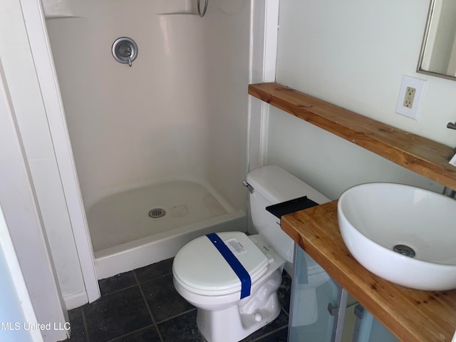 bathroom featuring toilet, vanity, a shower, and tile patterned floors