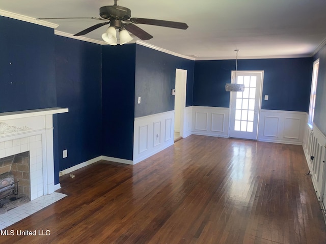 unfurnished living room featuring ornamental molding, a tiled fireplace, dark hardwood / wood-style floors, and ceiling fan