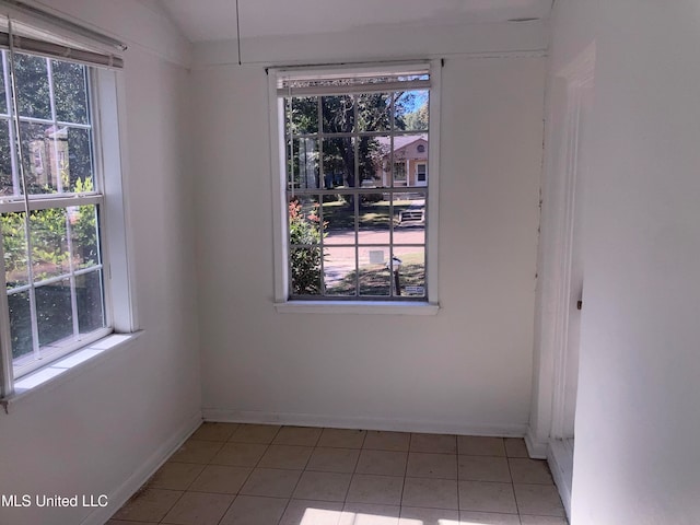 tiled empty room featuring lofted ceiling and a healthy amount of sunlight