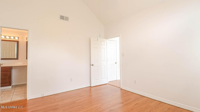 unfurnished bedroom with light wood-style floors, visible vents, high vaulted ceiling, and baseboards