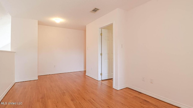 unfurnished room featuring light wood-style flooring, visible vents, and baseboards