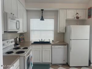 kitchen featuring white cabinets, white appliances, pendant lighting, and a sink