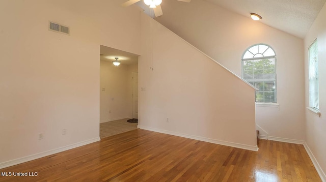 unfurnished room featuring lofted ceiling, wood finished floors, visible vents, and baseboards