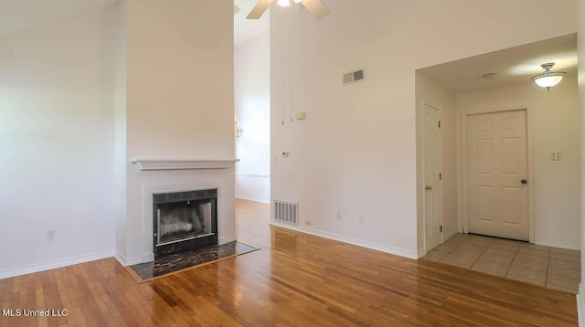 unfurnished living room featuring baseboards, a fireplace with flush hearth, visible vents, and wood finished floors