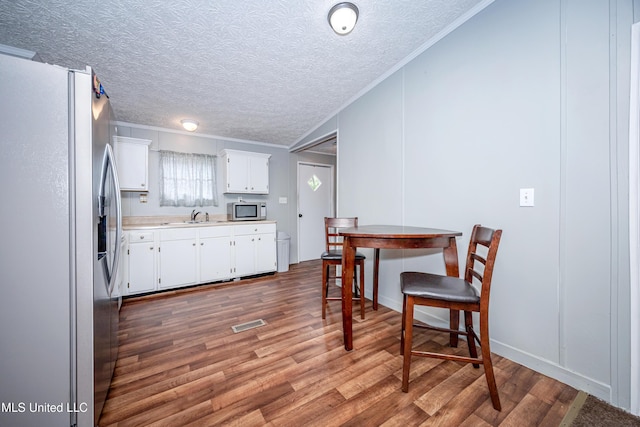 kitchen featuring wood finished floors, appliances with stainless steel finishes, ornamental molding, and a sink