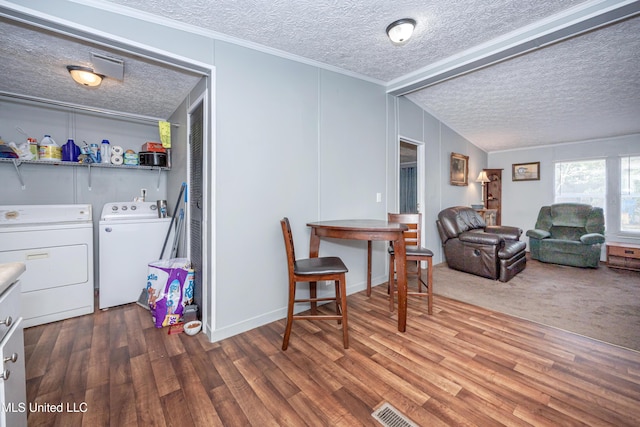 interior space with a textured ceiling, washing machine and dryer, visible vents, wood finished floors, and ornamental molding