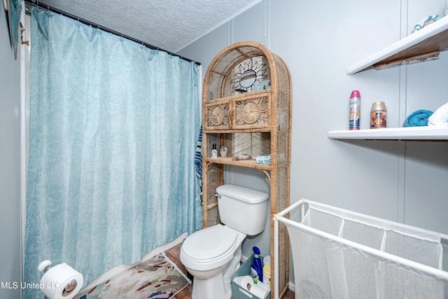 bathroom featuring toilet, a shower with shower curtain, and a textured ceiling