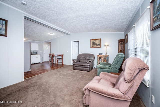 living room with dark colored carpet, a textured ceiling, and ornamental molding