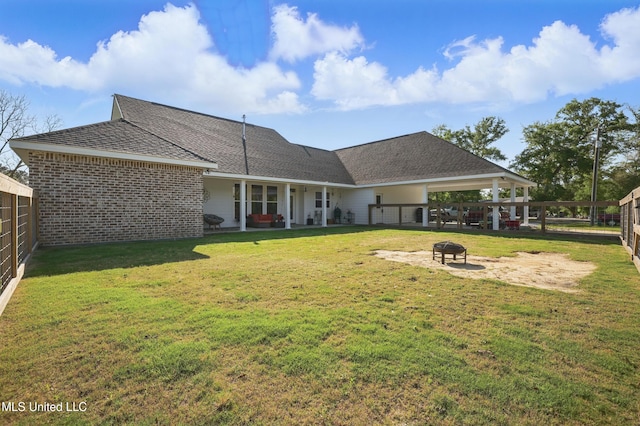 13240 Wolf River Rd, Gulfport, MS 39503 - rear view of house featuring a yard, a shingled roof, a fenced backyard, and an outdoor fire pit