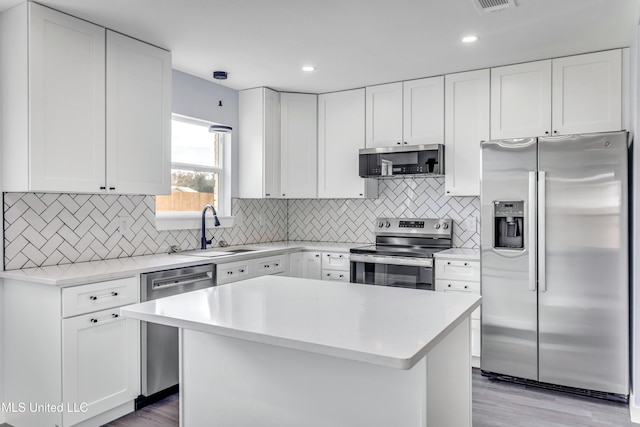 kitchen with decorative backsplash, appliances with stainless steel finishes, white cabinetry, and sink