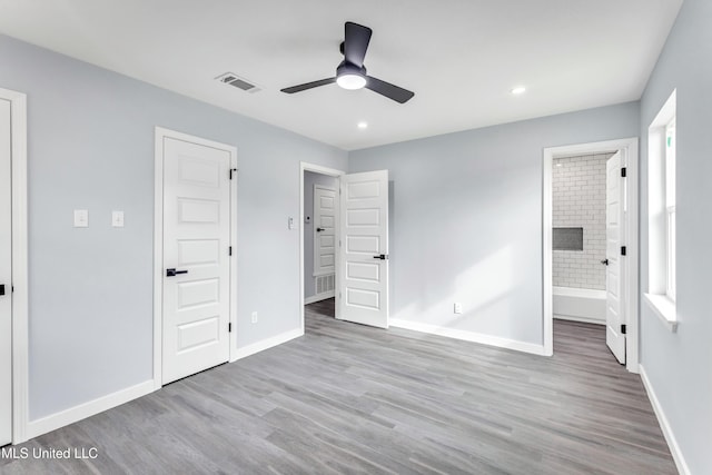 unfurnished bedroom with ceiling fan, light wood-type flooring, and ensuite bath