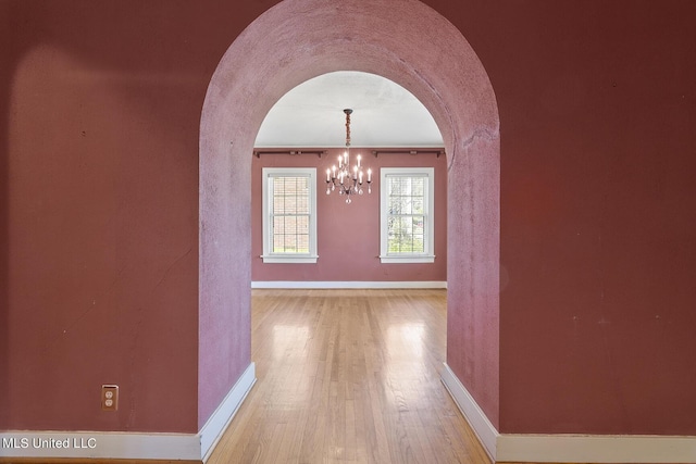 1521 Riverside Dr, Jackson, MS 39202 - hall with an inviting chandelier, wood finished floors, baseboards, and arched walkways