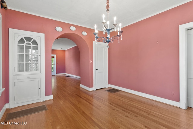 unfurnished dining area featuring ornamental molding, hardwood / wood-style flooring, and a chandelier