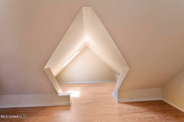 bonus room with lofted ceiling and light wood-type flooring