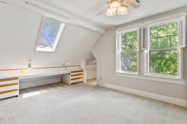 additional living space featuring vaulted ceiling with skylight, light colored carpet, and ceiling fan